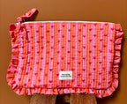 Grande pochette cœur rose et rouge à volant maison Augustin Devant un mur terracota et posé sur un tabouret 