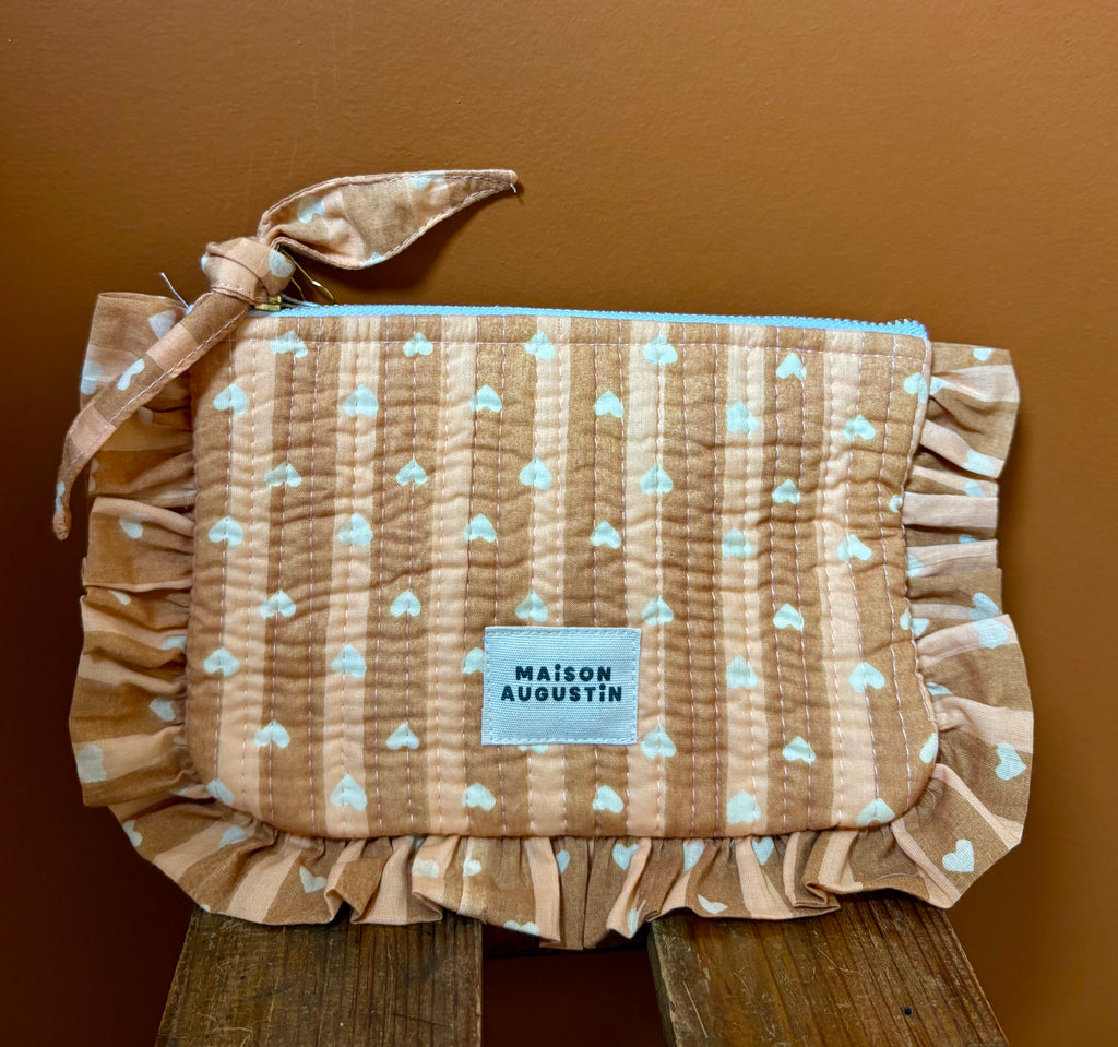 Petite pochette à volant cœur beige love maison Augustin zippée Sur fond terracotta et poser sur un tabouret bois 
