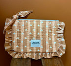 Petite pochette à volant cœur beige love maison Augustin zippée Sur fond terracotta et poser sur un tabouret bois 