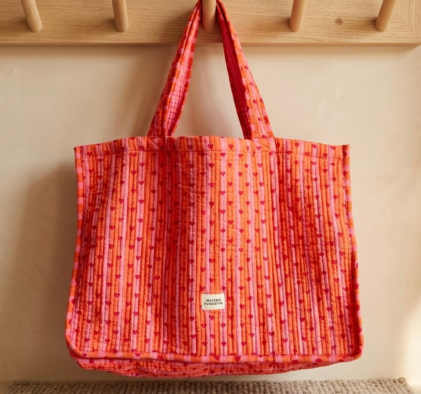 Sac cœur love pop rouge et rose maison Augustin Suspendu sur porte manteau en bois devant un mur beige 