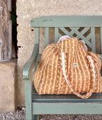 Sac week-end maternité cœur love beige  maison Augustin Posé sur un banc en bois vert d’eau 